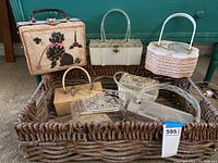 Overview of six main purses and two evening clutches inside woven basket