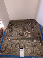 Assorted silver-tone bracelets, necklaces, earrings, and pendants laid out on wooden surface