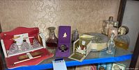 Wide shelf view showing travel grooming kit, cut glass decanter, Shalimar box, and other perfume bottles
