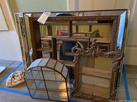 Overview of all items: arched metal glass case, ornate wood display case, wood-framed mirrored wall shelf, plaster cherub relief