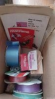 Photo of the crafting materials showing the macrame instruction book, various ribbons, and crafting instruction sheets