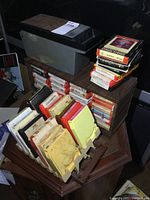 Photo showing multiple stacks and rows of vintage 8 track tape cartridges in various colored cases on a wooden table.