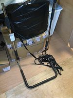 Black metal bed safety rail with padded grips and attached straps fitted under mattress.