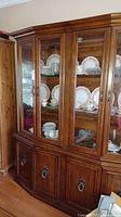 Full view of the wooden cabinet and hutch with glass doors and displayed china.