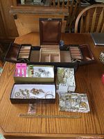Photo of all jewelry items displayed around and inside the open brown leather jewelry box with multiple compartments.