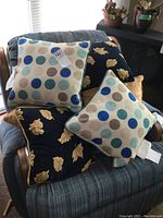Set of three pairs of throw cushions on a chair showing polka dot cushions and gold leaf patterned cushions.
