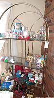 Full view of metal and glass display shelf holding various items, showing the overall condition and style of the shelving unit.