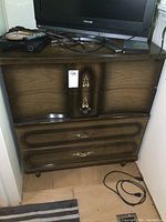 Front view of the vintage dresser showing two of the four drawers with brass handles, wood grain finish, some wear and tear visible.