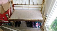 Full view of metal framed bench with cushioned seat and shoes placed underneath (shoes not included).