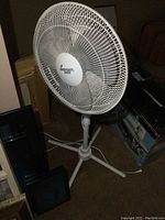 White Comfort Zone 42 inch pedestal fan standing on a tripod base with power cord visible on carpet floor.