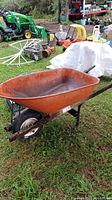 Side view showing metal basin, single wheel, and wood handles of the wheelbarrow outdoors on grass.