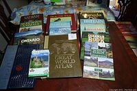 Books laid out on table showing titles relating to nature, world atlas, and travel guides for Canada, Britain, Germany.