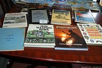 All 9 war books and 2 military manuals laid out on a table showing covers and titles for cataloging.