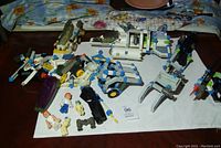 Photo of several assembled vintage Construx vehicles including a claw machine, small plane, and wheeled machine alongside small figures.