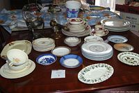 Wide view of collection showing stacked plates, cups, and the glass bowl with silver stand along with candle sconce