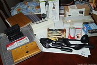 Overview of kitchen items including boxed Ronco Steamer Basket, Cuisinart hand blender, Farberware cutlery set, and several utensils and tools.