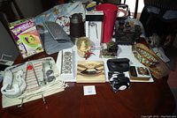 Full view of all items on a table showing thermos, wicker baskets, paint kit, metal mesh wall hangers, snow globe, and assorted small items.