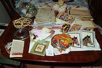 View of entire collection on table showing embroidery hoops, assorted embroidery floss, printed needlework canvas, knitting needles, old magazines, and patterns.