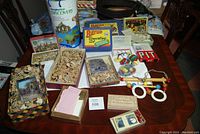 Overall display of all lot contents on table including building sets, puzzles, toys, and games.