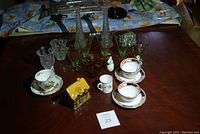 Full view of the lot with teacups, glassware, candle holders, green glasses, vases, and ceramic house decanter.