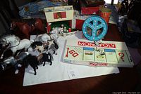 Photo showing plastic horses, Fisher Price barn and silo, Monopoly board, and peace sign light.