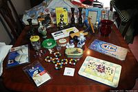 Overview photo showing the lot of vases, tins, candle holders, Coca-Cola bottles, shark frame and other assorted items on a wooden dining table.