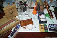 Overview of lots showing wooden humidor box, cigarette roller box, various glass vases, ceramic dishes, bronze sculpture, golf gloves, plant waterer and wine holder.