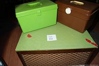 Photo of three sewing storage boxes: one large wood box with a padded green lid and fabric sides, and two smaller plastic boxes, one bright green and one brown.