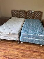 Photo showing Drexel king headboard with two different twin mattress sets placed side-by-side, including box springs and frames.