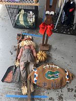 Photo showing fabric scarecrow, wooden reindeer, glittery gold pumpkin, wooden football sign with Florida Gators theme, and metal shovel with Halloween pumpkin design