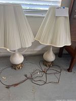 Pair of vintage matching table lamps with pleated cream fabric shades and ceramic bases on gold ornate feet