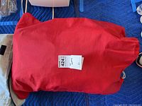 Red fabric bag containing the queen size Deluxe Aerobed with drawstring closure.