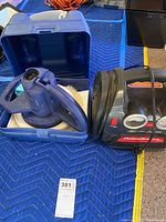 Lot items displayed on protective cloth: Chamberlain Waxmaster random orbital waxer/polisher with blue carrying case on the left, black and red auto accessory power station with gauges on the right.