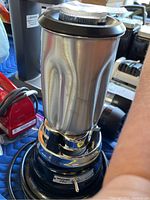 Waring Pro blender showing stainless steel jar and lid on blue metallic base.