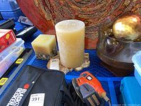 View of large beige pillar candle, square candles with embedded stones, glass decor with gold spheres