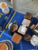 Photo of electric tea kettle and four metal canisters on moving blanket.