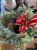 Photo of the decorated holiday wreath showing pine cones, red berries, greenery, and large red bow