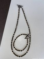 Photo of beaded necklace with small silver chain segments and black beads on white background
