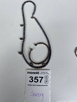 Beaded necklace with dangling accents and matching beaded bracelet laid flat on white background with lot tag visible.