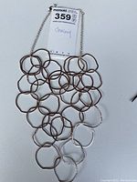 Top-down photo of silver plated necklace with irregular linked circles on a white background