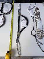 Full length view of the stone beaded necklace approximately 24 inches long, displayed with a measuring tape for scale along with other jewelry items nearby.