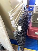 Black metal foldable pet crate and white adjustable indoor pet gate leaning against a cabinet and next to other pet carriers