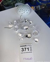 Photo of 11 Swarovski miniature crystal figurines arranged on a table with a trinket box in the background and a MaxSold lot label visible