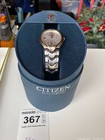 Front view of Citizen Eco-Drive men's wristwatch showing the silver dial with Arabic numerals and date window, mounted on original packaging box.