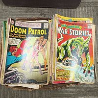 Box filled with a large stack of vintage comic books, showing Doom Patrol and Star Spangled War Stories covers.