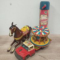 Nomura friction truck with tin carnival carousel, Tico crank kaleidoscope, and Haji windup horse displayed together