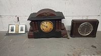 Photo of three clocks: a black vintage mantel clock, a wooden case clock, and a silver-tone desk clock with barometer and thermometer.