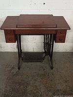 Full view of the wooden sewing machine cabinet with foldable top and drawers on both sides.