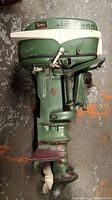 Top side view of green Johnson outboard motor with white throttle handle and logo visible.