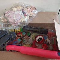 Box filled with assorted vintage toys including doll, flashlight, and toy glove